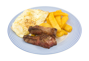 Fried strip steak and eggs with potatoes on blue striped plate