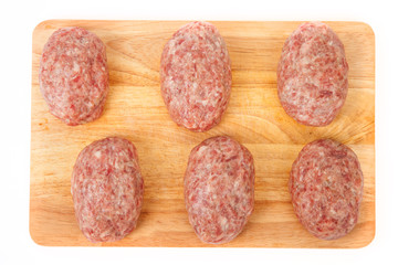 raw meat patties on a wooden board on a white background