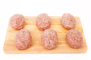 raw meat patties on a wooden board on a white background