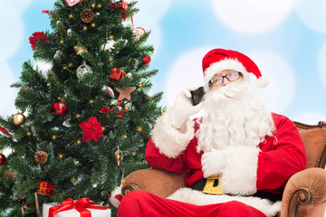 santa claus with smartphone and christmas tree
