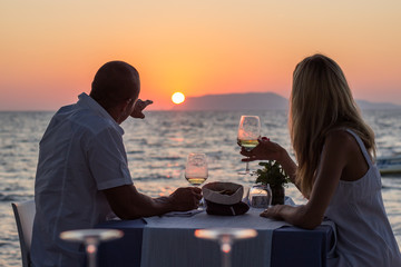 Couple drinking wine at beach restaurant  on sunset