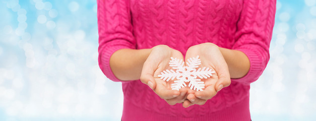 close up of woman in sweater holding snowflake