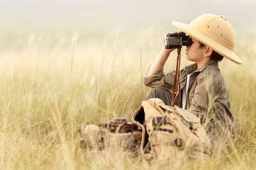 Boy looking through binoculars in a thick gray grass