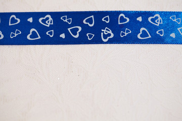 blue ribbon with hearts on a light background