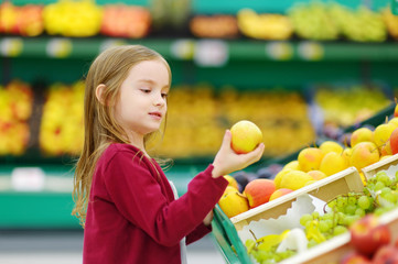 Fototapeta na wymiar Little girl choosing an apple in a store