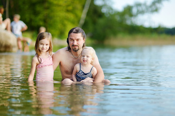 Fototapeta na wymiar Two sisters and their father having fun in a river