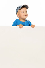 Cute little boy is above white blank poster looking up