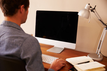 Man Sitting At Desk Working At Computer In Home Office