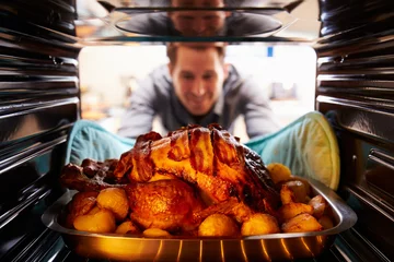 Foto op Plexiglas Man Taking Roast Turkey Out Of The Oven © Monkey Business