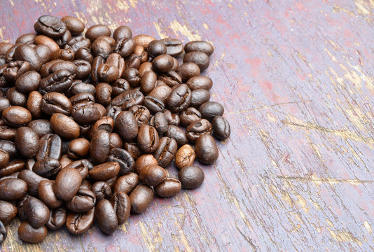 Roasted coffee beans on textured wood.