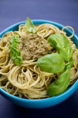 Close-up of spaghetti with pesto sauce and fresh basil leaves