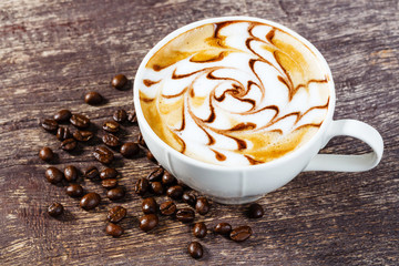Cup of coffee and roasted bean on old wooden table