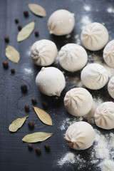 Raw khinkali with dried bay leaves and black pepper, close-up