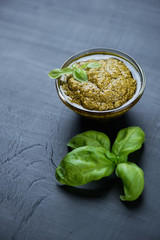 Basil pesto sauce over black wooden surface, studio shot