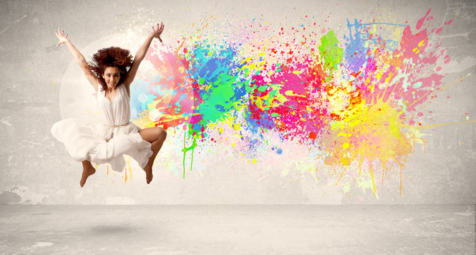 Happy teenager jumping with colorful ink splatter on urban backg