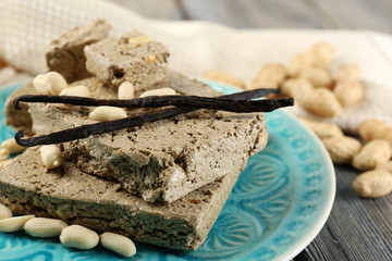 Sunflower halva with peanuts on plate, on wooden background