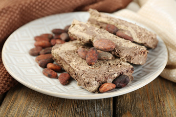 Sunflower halva with cocoa on plate, on wooden background