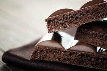 Tasty porous chocolate on wooden table