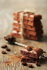 Tasty porous chocolate with coffee beans, on wooden table