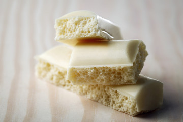 Tasty white porous chocolate on wooden table, close up
