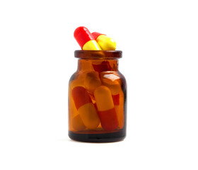 Medicine glass bottle with colored pills, isolated on white back
