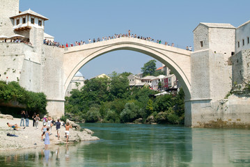 Tourists watching at people who jump from the bridge of Mostar