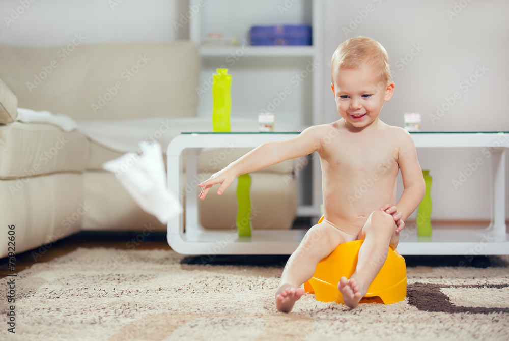 Wall mural Smiling baby sitting on chamber pot