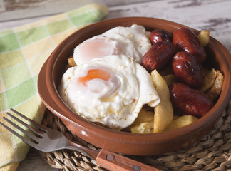 Eggs with french fries and small sausages
