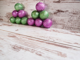 Pink and green christmas balls in a stack over wooden background