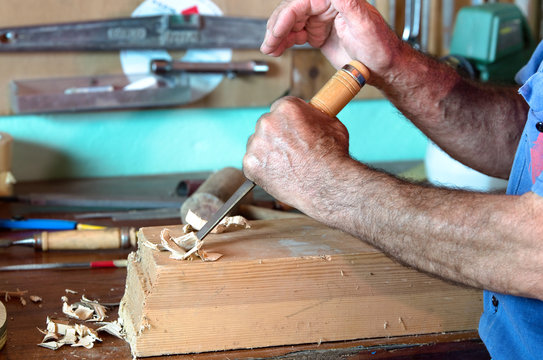 cabinetmaker carving a piece of wood with chisel and using his h