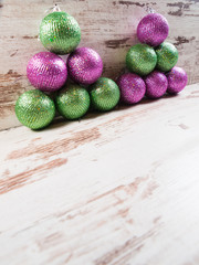 Pink and green christmas balls in a stack over wooden background