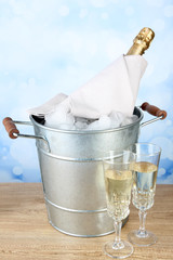 Bottle of champagne in metal ice bucket and two glasses