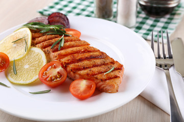 Grilled salmon and vegetables on plate on wooden background