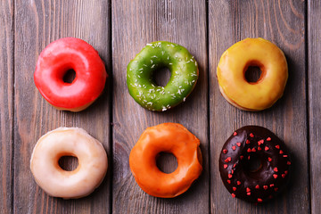 Delicious donuts with glaze on wooden background