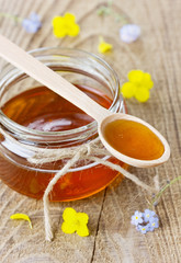 Honey in a wooden spoon and jar on a wooden rustic background