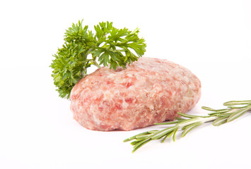 raw meat cutlet with a sprig of parsley and rosemary on a white