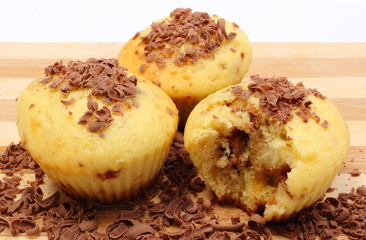Fresh baked muffins and grated chocolate on wooden cutting board