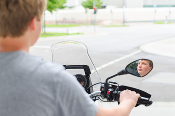 Fototapeta na wymiar Teenager riding a motorcycle at street junction