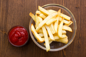 Bowl of chips and ketchup on wooden table top views