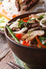 Asian food: rice noodles with shiitake, meat and vegetables