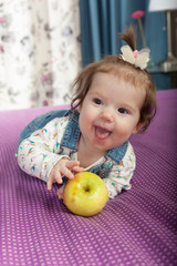 Fototapeta premium Little baby girl with an apple smiling indoors