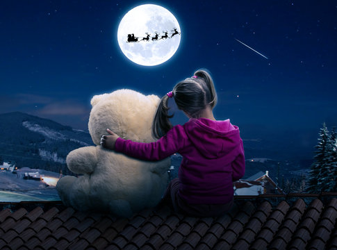 Small cute girl sitting on the roof with toy bear