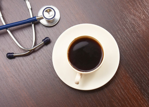 A cup of coffee and a statoscope on a desk, from above