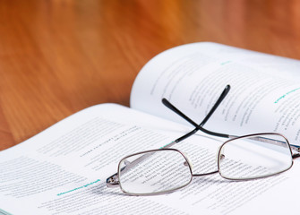 book with glasses on the desk against books