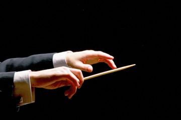 Concert conductor hands with a baton isolated on a black