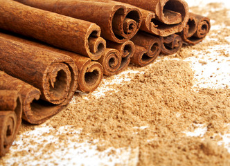 Cinnamon sticks with its dust around it over a white background