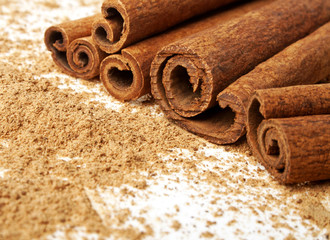 Cinnamon sticks with its dust around it over a white background