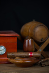 Cuban cigar in ashtray with humidor and rum barrel