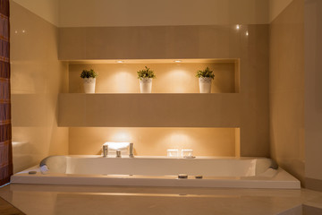 Fototapeta na wymiar Ceramic bathtub in illuminated bathroom