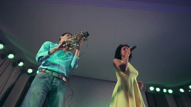Black woman singer and her saxophone player performing on stage.
